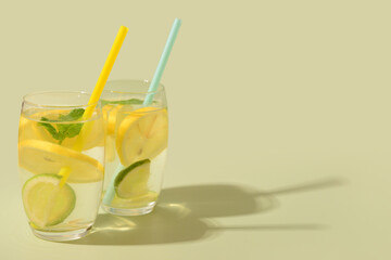Glasses of tasty lemonade with mint and lime on green background