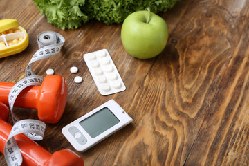 Composition with glucometer, measuring tape, dumbbells and pills on wooden background