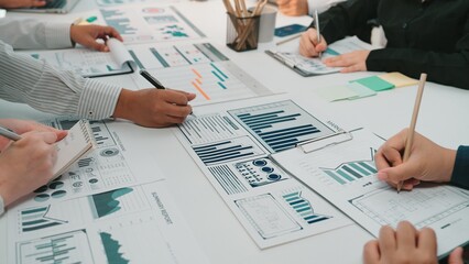 Close-up view of a collaborative team engaging in data analysis with charts and graphs, showcasing teamwork and strategic planning in an office environment. SACTR