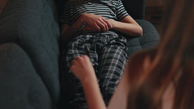 Playful siblings wrestle on living room couch, sister tickles brother causing infectious laughter and capturing a genuine moment of family bonding