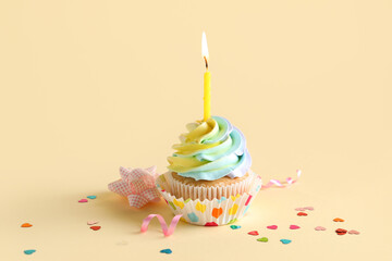 Delicious birthday cupcake with burning candle on yellow background