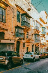 Fototapeta premium Typical narrow streets with colorful balconies in VallettaTypical narrow streets with colorful balconies. Narrow streets with colourful window boxes in Valetta, MaltaTraditional Maltese balconies in V