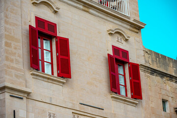 Red traditional maltese balconies in sunny day. Facade of old traditional building with red windows and balconies in Valletta, Malta
