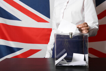 Voting young woman near ballot box against UK flag, closeup