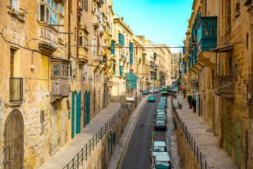 Obraz premium Typical narrow streets with colorful balconies in VallettaTypical narrow streets with colorful balconies. Narrow streets with colourful window boxes in Valetta, Malta Traditional Maltese balconies