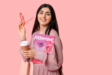 Happy smiling young woman with shopping bag, cup of coffee and magazine on pink background