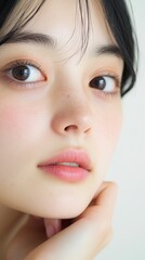 Fototapeta premium Contemplative Asian Woman with Thoughtful Expression Resting Chin on Hand on Plain White Background - Versatile Conceptual Portrait