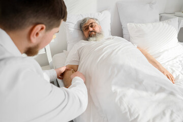 Obraz premium Senior man with drip infusion and caregiver lying in bedroom