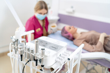 Obraz premium Wellness center skin treatment. A client relaxes during a skin treatment while a professional nurse prepares tools and enjoys a beverage nearby.