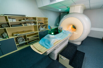 MRI machine for diagnostics. A patient is positioned on an MRI table in a diagnostic room equipped...