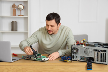 Male technician repairing computer board at table in service center