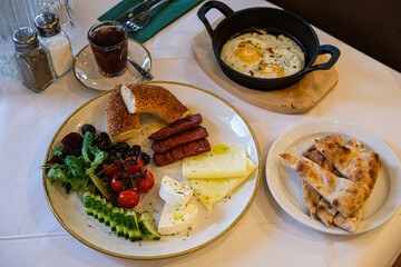 Turkish or Mediterranean style breakfast. Turkish breakfast. Variety of fresh vegetables, olives, cheeses, jams and spreads on a small plates on a white tablecloth covered table. Traditional turkish 