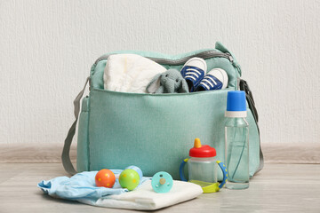 Baby bag with bottle of water on floor against grey background
