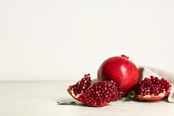Fresh ripe pomegranates and leaves on white wooden table