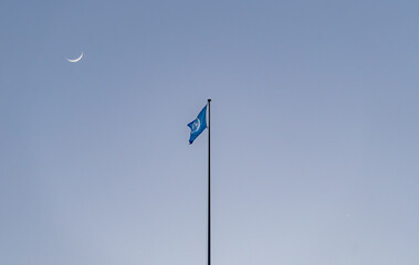 United Nations flag under crescent moon and Venus at dusk