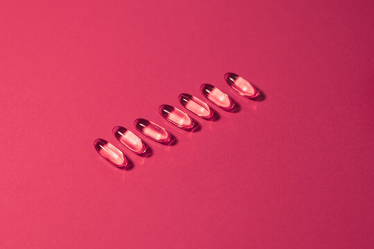 Pink gel capsules on a vibrant pink background