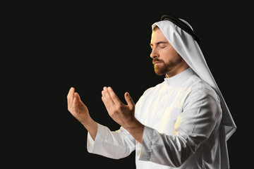 Young Muslim man praying on black background. Ramadan celebration