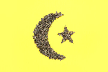 Crescent and star made of dry green tea on yellow background. Ramadan celebration