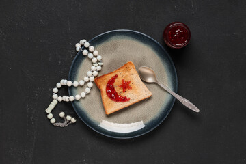 Plate with tasty toast, jam and prayer beads on dark background. Ramadan celebration