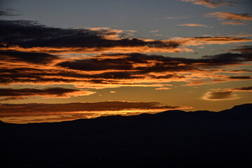 Dramatic sunrise with glowing clouds over mountain silhouette
