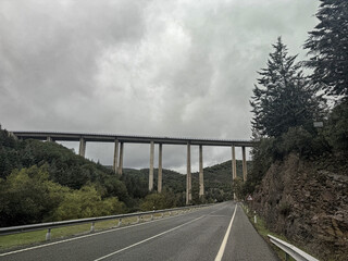 High viaduct bridge crossing over a scenic valley under cloudy skies