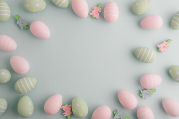 Pastel easter eggs and flowers on green background. Top view