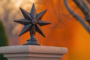Elaborate bronze star atop stone pillar against warm sunset hues creates a sophisticated architectural detail with a vintage, decorative charm and natural beauty.
