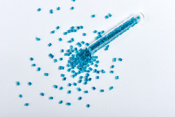 Clear blue masterbatch granules spilled from glass tube and isolated on white background. Color pigment carrier polymer in plastic industry. Perfect for plastic company catalog design