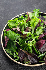 Fresh salad leaves mix salad juicy healthy snack micro greens, arugula, lettuce, oak leaf, green leaf salad tasty food background on the table rustic food top view copy space vegetarian and vegan