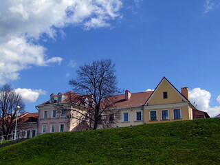 Obraz premium Historical buildings in Trinity Suburb, Minsk, Belarus, with a green hill and a blue sky with white clouds