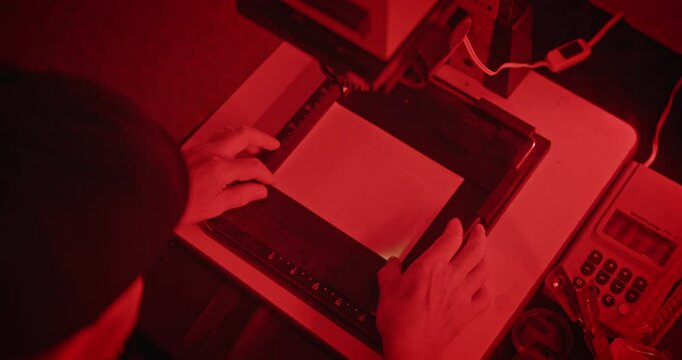 Elderly Man Developing Film in a Vintage Darkroom Under Red Safelight