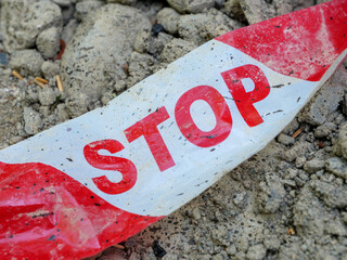 Safety tape with STOP warning placed on uneven ground at a construction site