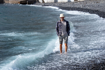 Introspective man stands knee-deep in turquoise waters, Coastal wanderer in checkered shirt and...