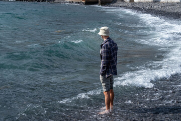 Introspective man stands knee-deep in turquoise waters, Coastal wanderer in checkered shirt and...