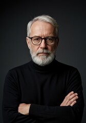 Obraz premium Thoughtful senior man with a beard and glasses stands confidently with arms crossed against a grey background.
