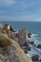Waves of the Black Sea crash on a rocky shore on a sunny day in Crimea.