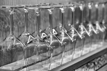 Transparent drinking glasses perfectly lined up on wooden shelves in a restaurant
