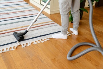 Teenager completes homework while vacuuming the living room in the afternoon sunlight on a weekend day