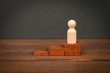 Wooden Figure on Stacked Blocks Representing Progress and Achievement Concept