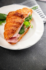 Sandwich croissant ham, cheese, green leaf salad delicious gourmet food background on the table rustic food top view copy space
