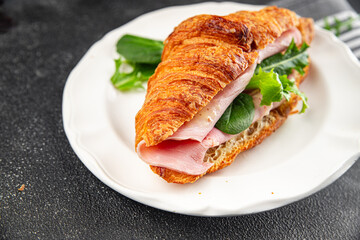 Sandwich croissant ham, cheese, green leaf salad delicious gourmet food background on the table rustic food top view copy space