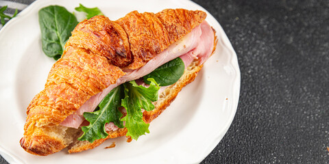 Sandwich croissant ham, cheese, green leaf salad delicious gourmet food background on the table rustic food top view copy space