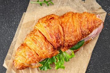 Sandwich croissant ham, cheese, green leaf salad delicious gourmet food background on the table rustic food top view copy space