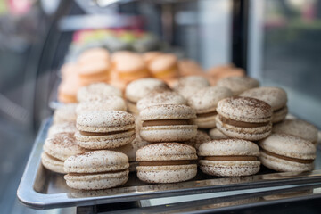 Large amount of pink macaron dessert cakes in refrigerator with glass display case, reflection and...