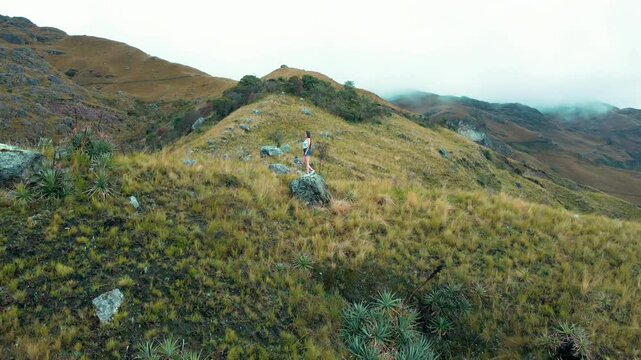Joven corriendo en la naturaleza entre monta&ntilde;as y paisajes m&aacute;gicos . Chica en shorts disfrutando el aire libre y el turismo en la monta&ntilde;a.estilo de vida saludable .video drone.