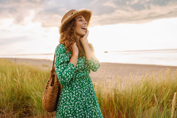 Happy woman  walking in the beach near tall grass. Flying hairs. Outdoor. Fashion style
