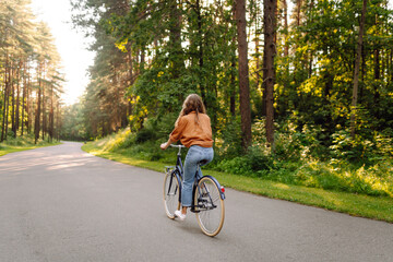 Young modern woman rides bicycle in the park. Sports activities. Taking care of environment