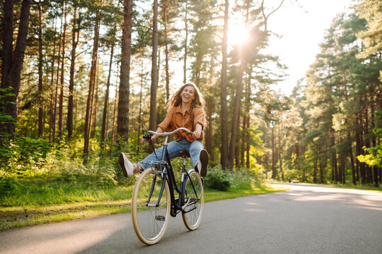 Young modern woman rides bicycle in the park. Sports activities. Taking care of environment
