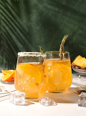Summer party concept. Tequila, rum and vodka cocktail with pineapple, orange, ice and rosemary...