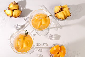 Cocktail with tequila, rum and vodka with pineapple slices, orange, ice and rosemary. Summer party concept. Diet drink for body detox and weight loss, advertising for a bar or cafe